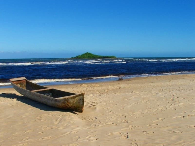 Praia de Caieiras com barco de pesca artesanal na areia e montanhas ao fundo