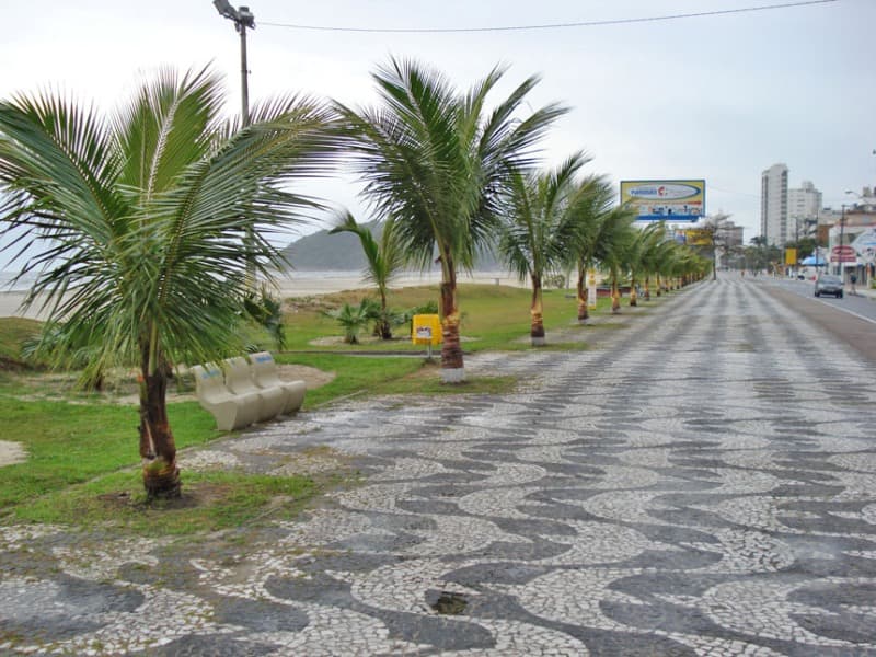 Avenida beira-mar com calçadão em mosaico português, palmeiras e faixa de praia ao lado
