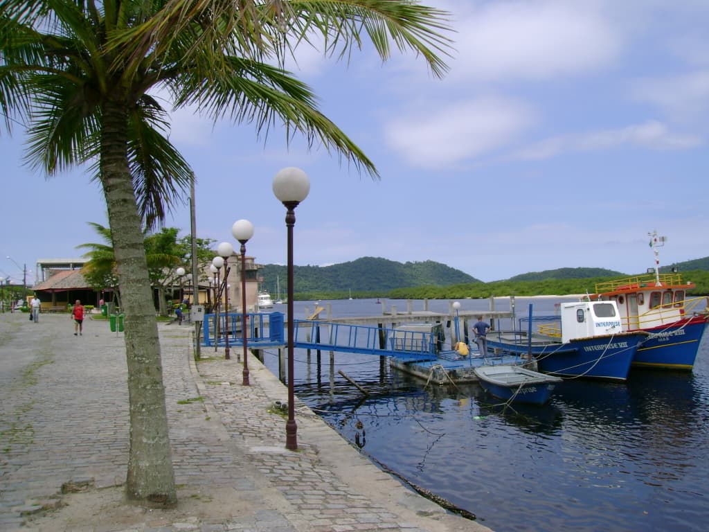 Calçadão da Rua da Praia com palmeiras e embarcações no Rio Itiberê em Paranaguá