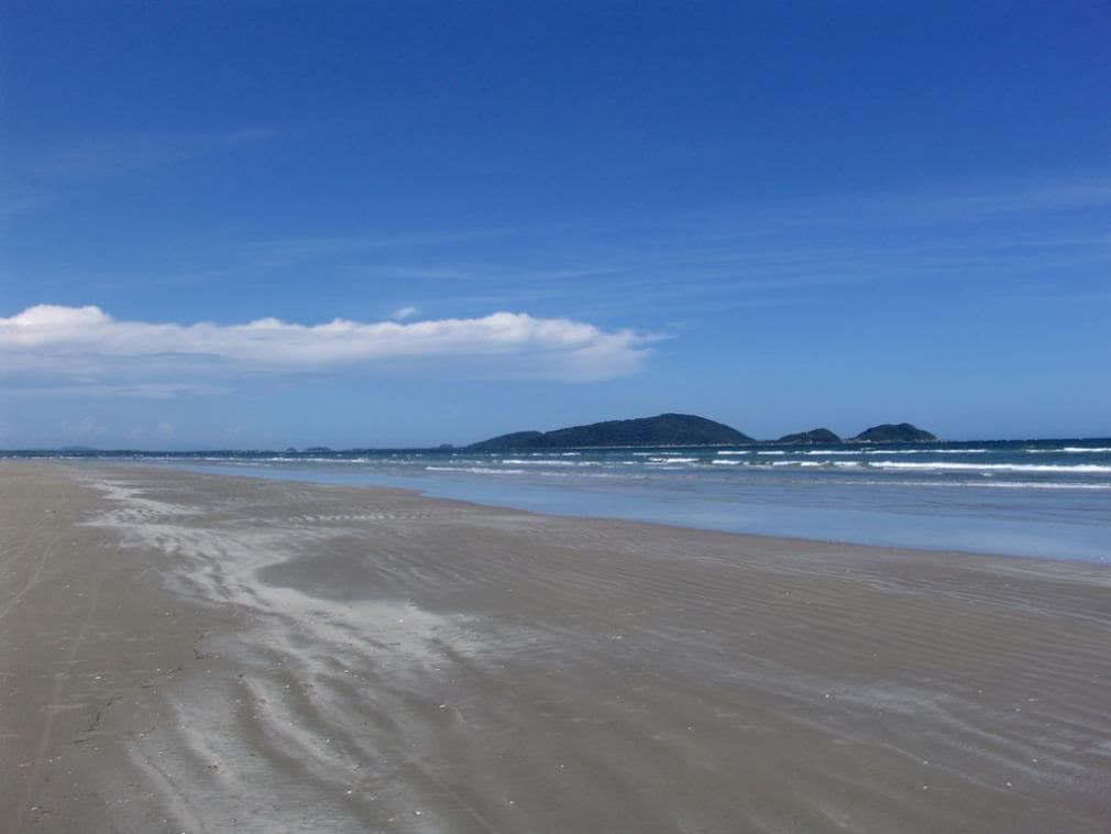 Praia ampla de areia com mar calmo no Balneário Ipanema
