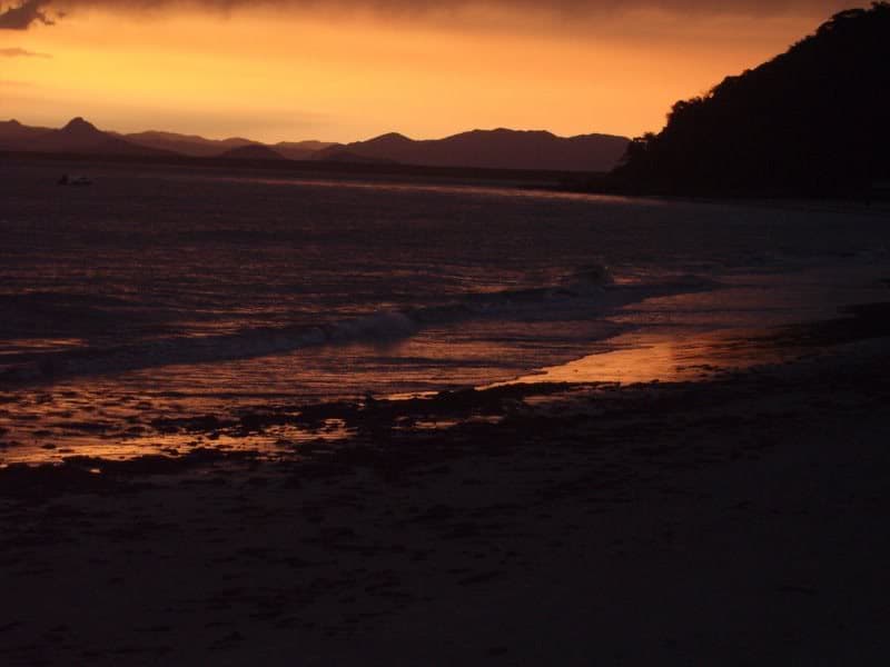 Pôr do sol no mar com silhuetas de montanhas ao fundo na Ilha do Mel